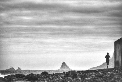 Rear view of silhouette man standing on desert against sky
