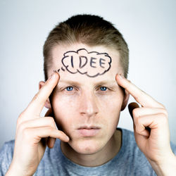 Close-up of young man with drawing on forehead against white background