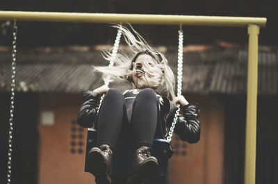 Cheerful young woman swinging at playground