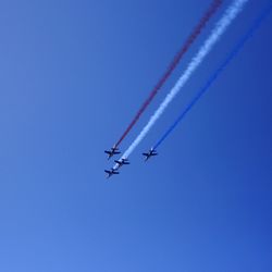 Low angle view of airshow against clear blue sky