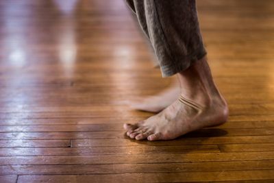 Low section of man standing on hardwood floor