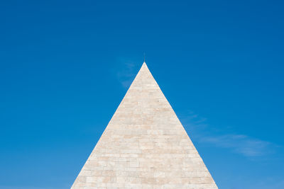 Low angle view of pyramid of cestius against blue sky