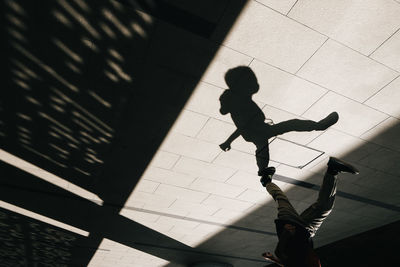 High angle view of silhouette people walking on tiled floor