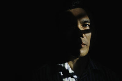 Close-up portrait of young woman against black background