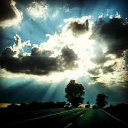 Road passing through landscape against cloudy sky