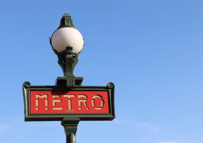 Low angle view of road sign against blue sky