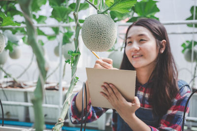 Woman standing by plants at greenhouse