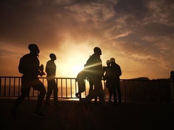 Silhouette people playing on beach against sky during sunset