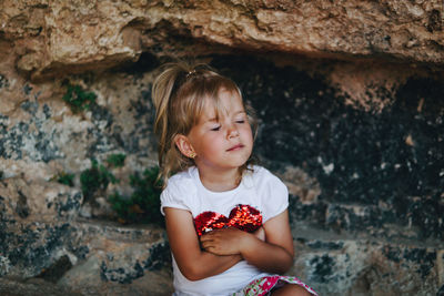 Girl looking away while standing against wall