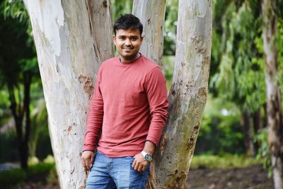 Portrait of man standing on tree trunk