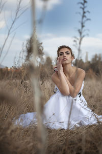 Thoughtful of young bride crouching on land