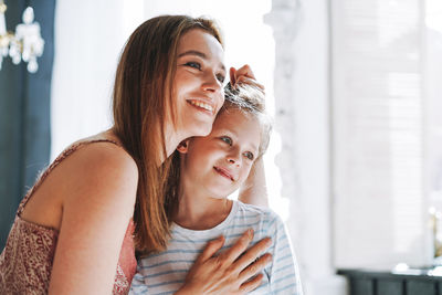 Young mother woman with long hair with little tween girl daughter in pajamas having fun at home