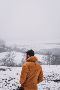 Rear view of man standing on snow covered landscape