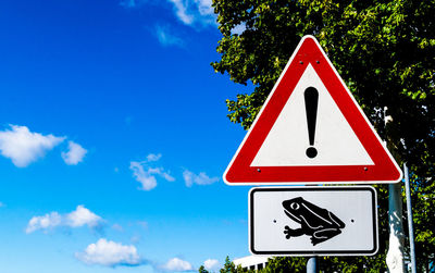 Close-up of road sign against blue sky