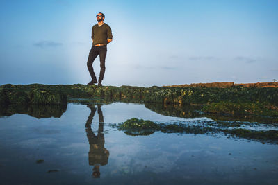 Full length of man standing by lake against sky