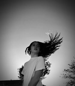 Young woman standing against sky