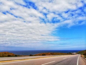 Empty road against cloudy sky