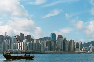 Sea by modern buildings against sky in city