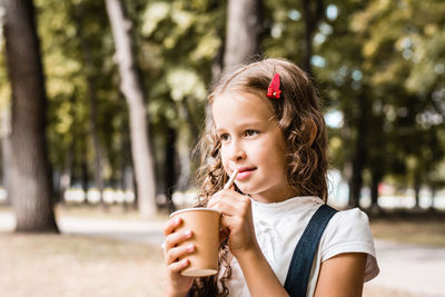 Schoolgirl drinking from an eco-friendly cup and straw in the park