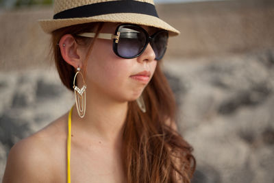 Close-up of young woman in sunglasses sitting at beach