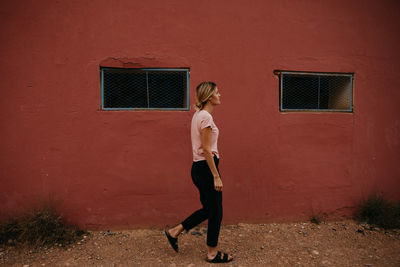 Full length of woman standing against building wall