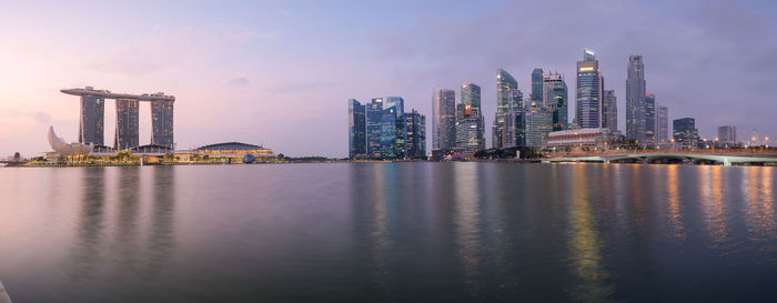 Sea by modern buildings against sky in city