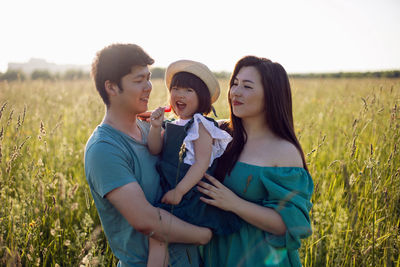 Korean family mom and father with a girl child daughter with candy lying on a green field in summer