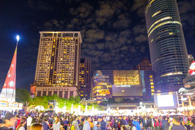 People on street against illuminated buildings at night