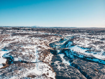 Aerial view of snow covered landscape against clear sky