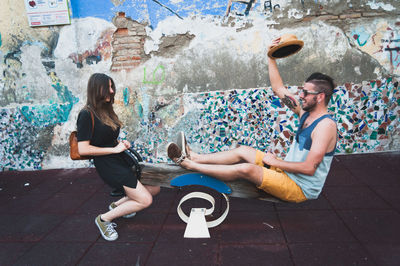 Happy friends playing seesaw against damaged wall