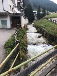 Walkway by river amidst buildings