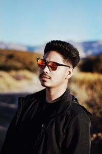 Close-up of young man wearing sunglasses against clear sky