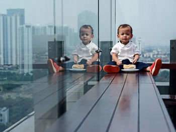 Portrait a baby boy enjoys breakfast on the balcony of a skyscraper.