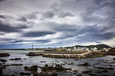 View of town by sea against storm clouds