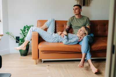 Young thoughtful family couple resting relaxed lying on the couch.