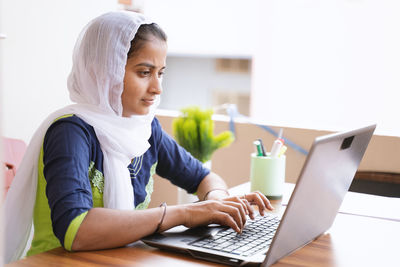 Young woman using mobile phone while sitting on table