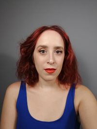 Portrait of beautiful young woman against gray background