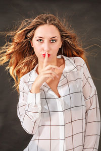 Portrait of young woman against black background