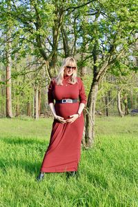 Portrait of woman with red umbrella standing on field