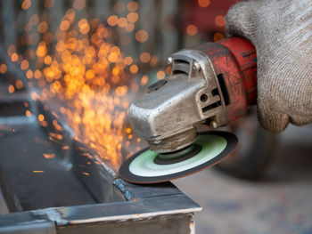 Low angle view of illuminated industry. worker grinding cutting metal sheet grinder machine welding 