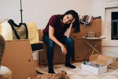 Portrait of smiling woman sitting on cardboard box at home