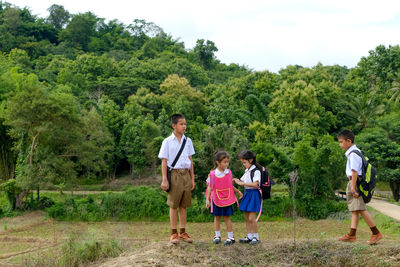 Children in school uniforms standing on field against trees