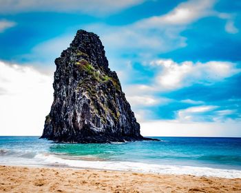 Rock formation on beach against sky