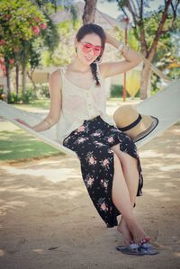 Pretty asian lady model seated on hammock white top beach resort summer wear fashionable