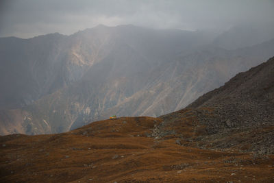 Small house on a mountainside in a huge alpine gorge in the fog in autumn