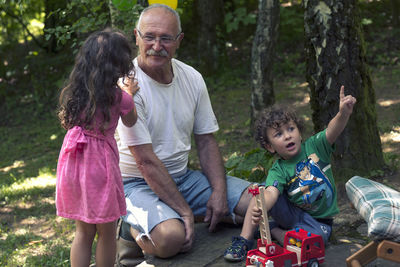 Full length of father and daughter sitting on tree