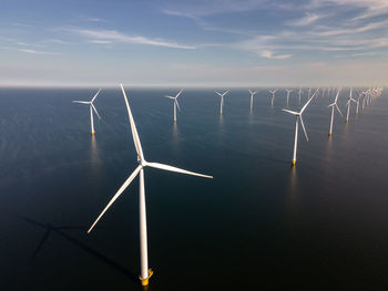 Wind turbines in sea against sky