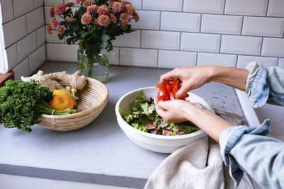 Cropped image of woman making salad at kitchen counter