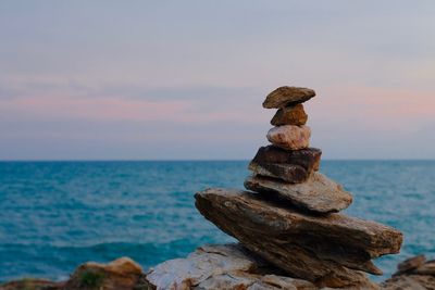 Stack of rocks in sea against sky