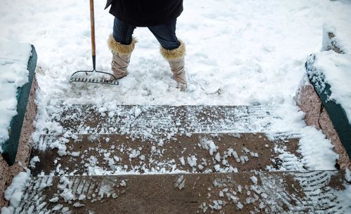 Low section of person with gardening fork on snow covered field